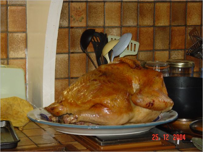 And there he is, in all his glory.  He is lying on the platter breast down where he will rest while Laura makes the gravy.  Just before serving the bird, he is carefully flipped over, put into the oven on a cookie sheet, and browned on his breast side for a few minutes.