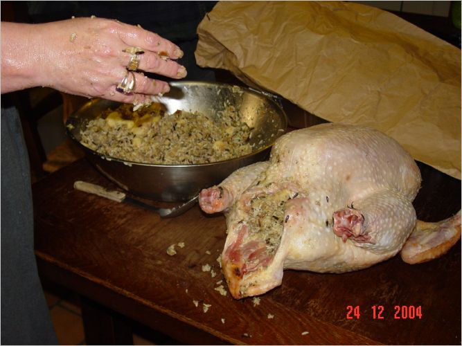 After the baking of the morning, the gift giving of the early evening, after a nice nap, it is time to begin getting the T Bird ready for Christmas Day.  Here Laura has made the dressing and is stuffing the bird.