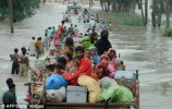 Pakistani flood survivors evacuate a flooded area in Bssera village near Muzaffargarh today.jpg