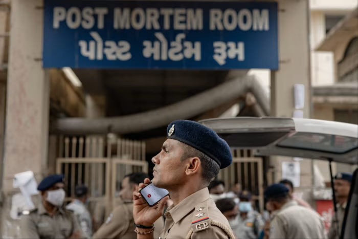 A police officer listens to his mobile phone outside the post mortem room of a hospital in Ahmedabad, India, on June 13 2025