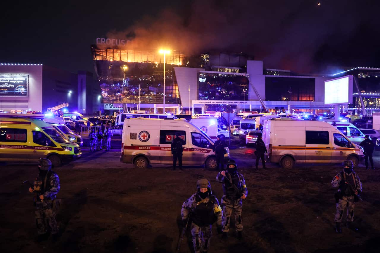 Soldiers stand in the foreground of a building on fire