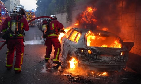 Firefighters tackle a burning car on the sidelines of a demonstration in Nanterre, west of Paris, after French police killed a teenager who refused to stop for a traffic check.