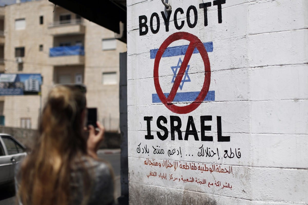 A tourist photographs a sign painted on a wall in the West Bank biblical town of Bethlehem on June 5, 2015, calling to boycott Israeli products coming from Jewish settlements [THOMAS COEX/AFP/Getty Images]
