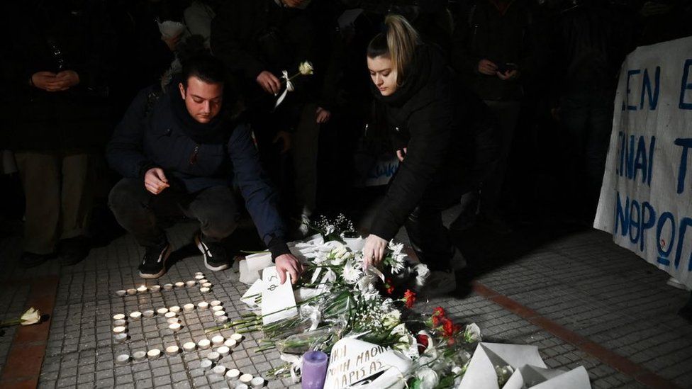 People light candles and lay flowers outside the railway station in Larissa on 1 March