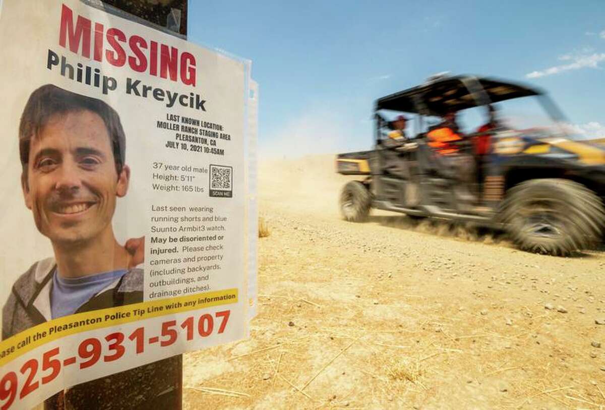 A search and rescue vehicle passes a poster for missing runner Philip Kreycik in Pleasanton in July..