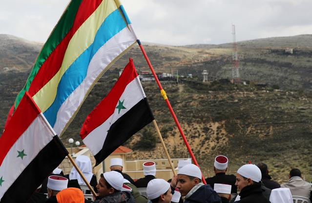 Members of the Druze community holds Syrian and Druze flags as they sit facing Syria, during a rally marking the anniversary of Israel's annexation of the Golan Heights in the Druze village of Majdal Shams, in the Israeli-occupied Golan Heights February 14, 2019. REUTERS/Ammar Awad