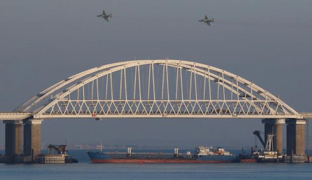 FILE PHOTO: Russian jet fighters fly over a bridge connecting the Russian mainland with the Crimean Peninsula with a cargo ship beneath it after three Ukrainian navy vessels were stopped by Russia from entering the Sea of Azov via the Kerch Strait in the Black Sea, Crimea November 25, 2018. REUTERS/Pavel Rebrov/File Photo