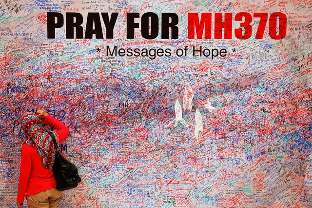 FILE PHOTO: A woman leaves a message of support and hope for the passengers of the missing Malaysia Airlines MH370 in central Kuala Lumpur March 16, 2014.  REUTERS/Damir Sagolj 