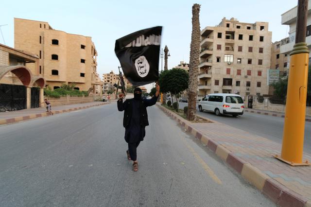 FILE PHOTO -  A member loyal to the Islamic State in Iraq and the Levant (ISIL) waves an ISIL flag in Raqqa, Syria June 29, 2014.  REUTERS/Stringer/File Photo