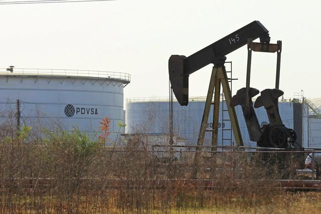 FILE PHOTO: An oil pumpjack and a tank with the corporate logo of state oil company PDVSA are seen in an oil facility in Lagunillas, Venezuela January 29, 2019. REUTERS/Isaac Urrutia/File Photo
