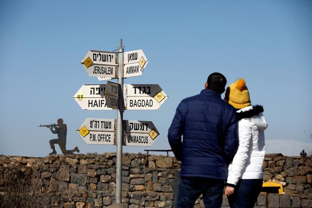 FILE PHOTO: A couple look towards signs pointing out distances to different cities,at an observation post in the Israeli-occupied Golan Heights, January 21, 2019. REUTERS/Amir Cohen/File Photo