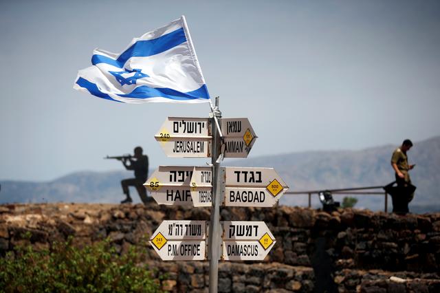 FILE PHOTO: An Israeli soldier stands next to signs pointing out distances to different cities, on Mount Bental, an observation post in the Israeli-occupied Golan Heights that overlooks the Syrian side of the Quneitra crossing, Israel May 10, 2018. REUTERS/Ronen Zvulun/File Photo