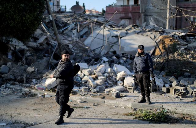 Palestinian policemen loyal to Hamas stand guard at the site of a Hamas-run insurance office after it was destroyed by an Israeli air strike in Gaza City March 26, 2019. REUTERS/Mohammed Salem