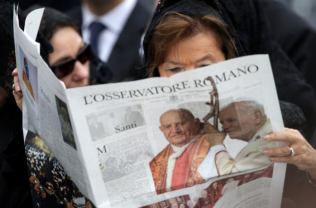 FILE PHOTO: A woman reads a copy of the Vatican newspaper L'Osservatore Romano as she waits for the canonisation ceremony in St Peter's Square at the Vatican, April 27, 2014. REUTERS/Max Rossi/File Photo