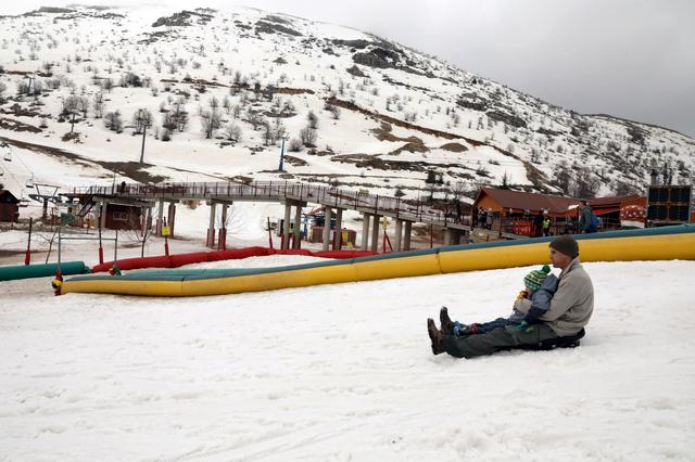 A man holds a young child as he sits on a snow sled at the Mount Hermon ski resort in the Israeli-occupied Golan Heights March 26, 2019. REUTERS/Ammar Awad