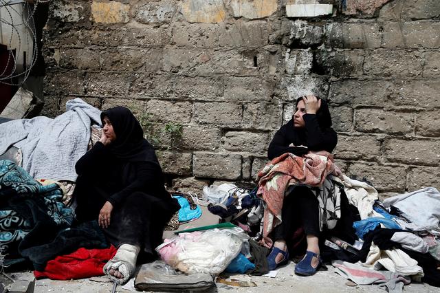 Palestinians sit with their belongings in a street outside their destroyed house after an Israeli missile targeted a nearby Hamas site, in Gaza City March 26, 2019. REUTERS/Mohammed Salem