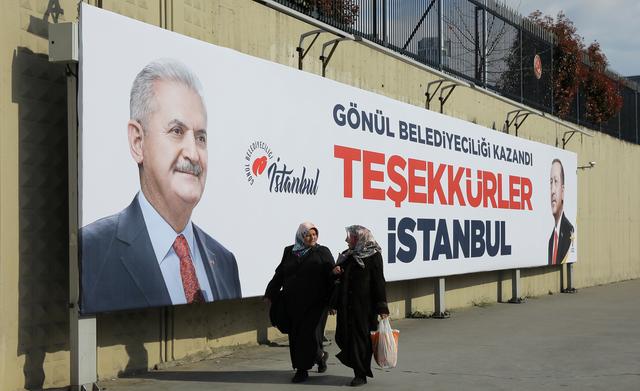 People walk past by AK Party billboards with pictures of Turkish President Tayyip Erdogan and mayoral candidate Binali Yildirim in Istanbul, Turkey, April 1, 2019. The billboards read:  Thank you Istanbul .  REUTERS/Huseyin Aldemir