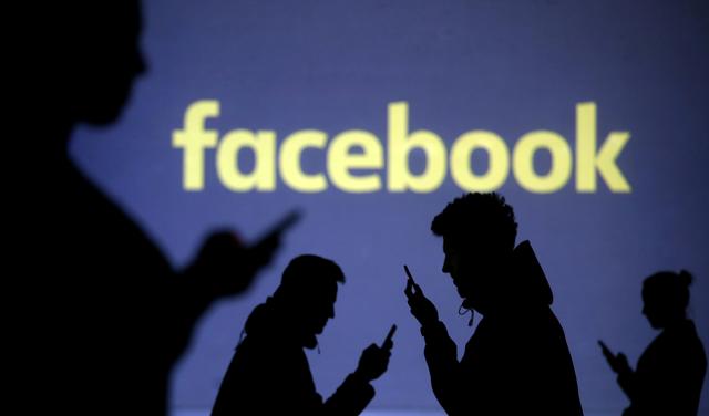 FILE PHOTO: Silhouettes of mobile users are seen next to a screen projection of the Facebook logo in this picture illustration taken March 28, 2018.  REUTERS/Dado Ruvic/Illustration/File Photo