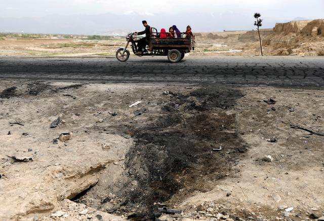 An Afghan family ride on a bike past the site of a car bomb attack where U.S. soldiers were killed near Bagram air base, Afghanistan April 9, 2019. REUTERS/Mohammad Ismail