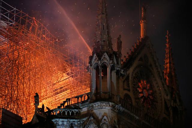 Sparks fill the air as Paris Fire brigade members spray water to extinguish flames as the Notre Dame Cathedral burns in Paris, France, April 15, 2019.   REUTERS/Philippe Wojazer