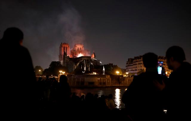 People watch as fire fighters douse flames of the burning Notre Dame Cathedral in Paris, France April 15, 2019. REUTERS/Benoit Tessier
