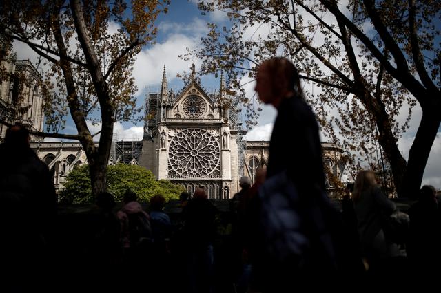 People gather as they look at Notre-Dame Cathedral two days after a massive fire devastated large parts of the gothic structure in Paris, France, April 17, 2019.   REUTERS/Benoit Tessier  