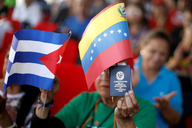FILE PHOTO: A supporter of Venezuela's President Nicolas Maduro holding a copy of the Venezuelan constitution and flags of Venezuela and Cuba, takes part in a gathering in support of his government outside the Miraflores Palace in Caracas, Venezuela January 26, 2019. REUTERS/Carlos Garcia Rawlins/File Photo