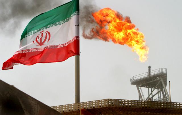 FILE PHOTO: A gas flare on an oil production platform in the Soroush oil fields is seen alongside an Iranian flag in the Gulf July 25, 2005. REUTERS/Raheb Homavandi/File Photo