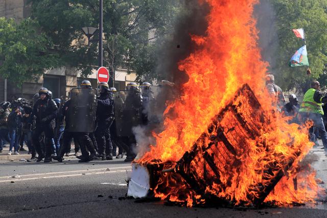 French CRS riot police stand guard next to a fire during clashes as part of the traditional May Day labour union march with French unions and yellow vests protesters in Paris, France, May 1, 2019.  REUTERS/Gonzalo Fuentes