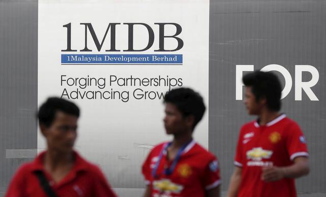 Men walk past a 1Malaysia Development Berhad (1MDB) billboard at the fund's flagship Tun Razak Exchange development in Kuala Lumpur March 1, 2015. REUTERS/Olivia Harris/File Photo