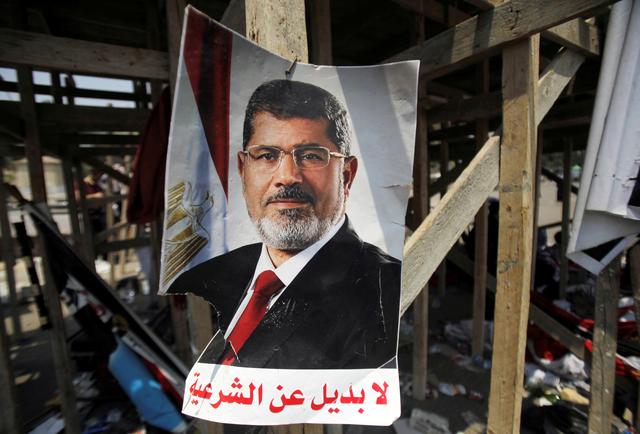FILE PHOTO: A poster of Egypt's President Mohamed Mursi reads, No substitute for the legitimacy is seen near members of the Muslim Brotherhood after night clashes with anti-Mursi around Cairo University and Nahdet Misr Square in Giza, on the outskirts of Cairo, Egypt July 3, 2013. REUTERS/Staff/File Photo