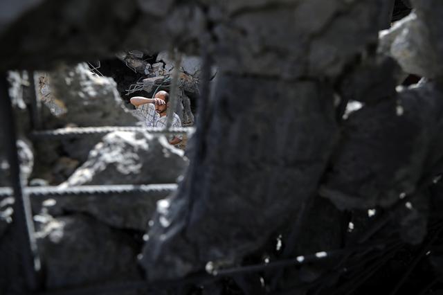 A Palestinian man is seen through the rubble of an apartment block that was hit by an Israeli air strike, in the northern Gaza Strip May 6, 2019. REUTERS/Mohammed Salem