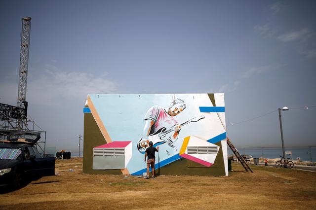 A man paints a mural on a structure that is located close to where the Eurovision Village, a space dedicated of fans of the upcoming Eurovision Song Contest, is being constructed in Tel Aviv, Israel May 6, 2019. REUTERS/Corinna Kern