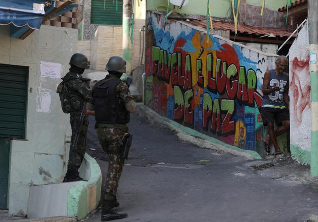 FILE PHOTO: Brazilian soldiers patrol in the Complexo da Penha slum in Rio de Janeiro, Brazil August 23, 2018. The graffiti reads: 'The favela is a place of peace.' REUTERS/Pilar Olivares/File Photo