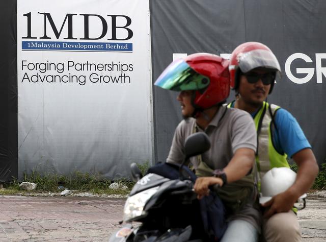 FILE PHOTO: Motorcyclists pass a 1Malaysia Development Berhad (1MDB) billboard at the Tun Razak Exchange development in Kuala Lumpur, Malaysia, February 3, 2016. REUTERS/Olivia Harris/File Photo