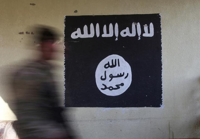 FILE PHOTO: A member of the Iraqi rapid response forces walks past a wall painted with the black flag commonly used by Islamic State militants, at a hospital damaged by clashes during a battle between Iraqi forces and Islamic State militants in the Wahda district of Mosul, Iraq, January 8, 2017.  REUTERS/Alaa Al-Marjani/File Photo