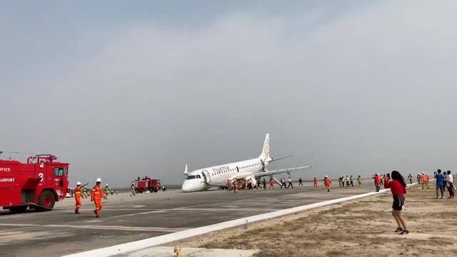 A passenger records the scene on her phone as firefighters attend to the scene after Myanmar National Airlines flight UB103 landed without a front wheel at Mandalay International Airport in Tada-U, Myanmar May 12, 2019 in this still image taken from social media video. Nay Min via REUTERS