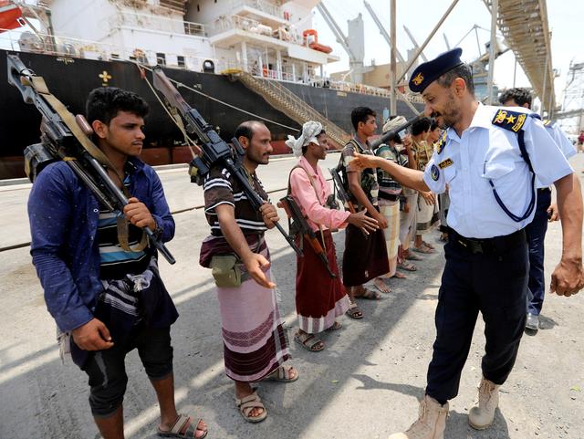 Yemeni coast guard officer shakes hands with members of the Houthi movement during withdrawal from Saleef port in Hodeidah province, Yemen May 11, 2019.  REUTERS/Abduljabbar Zeyad 
