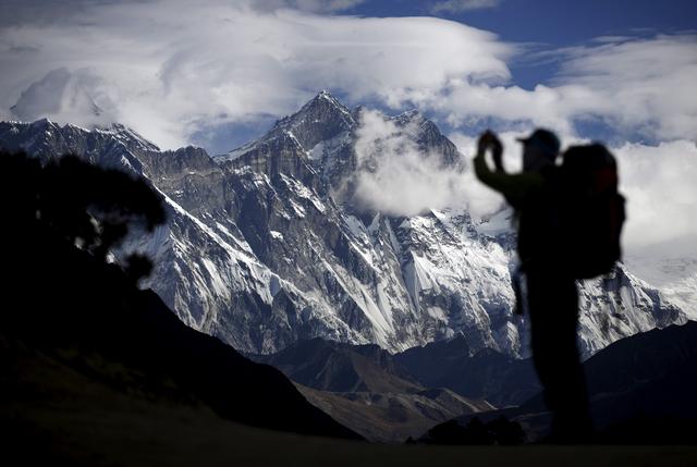 FILE PHOTO: A tourist is silhouetted as he takes pictures of Mount Nuptse (C) as Mount Everest (L) is covered with clouds in Solukhumbu district, also known as the Everest region, in this picture taken November 30, 2015.  REUTERS/File Photo