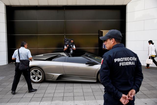 A police officer stands near a Lamborghini Murcielago 2007, part of the fleet of vehicles seized by the government from politicians and organized crime as part of an auction in Mexico City, Mexico May 21, 2019. REUTERS/Carlos Jasso
