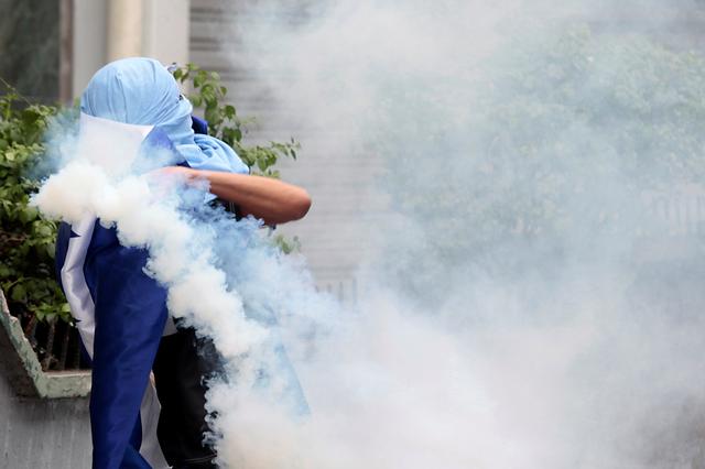 A demonstrator throws back tear gas canister fired by riot police during a protest against President Juan Orlando Hernandez government's plans to privatize healthcare and education, in Tegucigalpa, Honduras May 31, 2019. REUTERS/Jorge Cabrera