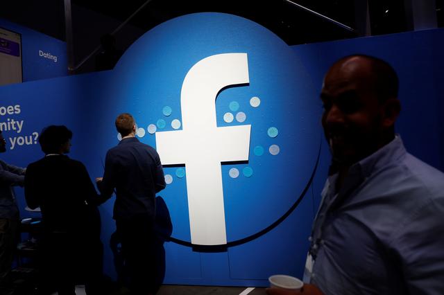FILE PHOTO: Attendees walk past a Facebook logo during Facebook Inc's F8 developers conference in San Jose, California, U.S., April 30, 2019.  REUTERS/Stephen Lam/File Photo