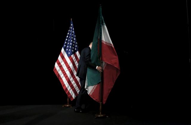 FILE PHOTO: A staff member removes the Iranian flag from the stage after a group picture with foreign ministers and representatives of the U.S., Iran, China, Russia, Britain, Germany, France and the European Union during Iran nuclear talks at the Vienna International Center in Vienna, Austria, July 14, 2015.  REUTERS/Carlos Barria/File Photo