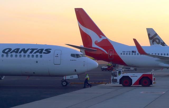 FILE PHOTO: Workers are seen near Qantas Airways, Australia's national carrier, Boeing 737-800 aircraft on the tarmac at Adelaide Airport, Australia, August 22, 2018. REUTERS/David Gray