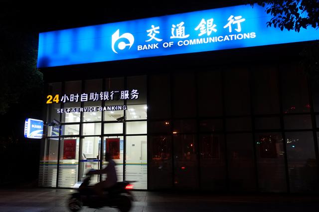 FILE PHOTO: A man rides past a Bank of Communications branch in Shanghai, China August 28, 2018.  REUTERS/Stringer  