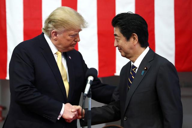 FILE PHOTO: U.S. President Donald Trump shakes hands with Japan's Prime Minister Shinzo Abe during delivering a speech to Japanese and U.S. troops as they aboard Japan Maritime Self-Defense Force's (JMSDF) helicopter carrier DDH-184 Kaga at JMSDF Yokosuka base in Yokosuka, south of Tokyo, Japan, May 28, 2019. REUTERS/Athit Perawongmetha/File Photo