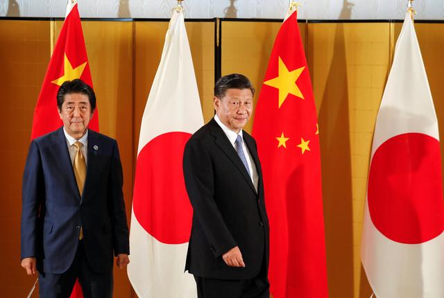 Chinese President Xi Jinping and Japanese Prime Minister Shinzo Abe look at media as they walk into the venue of their talks at a Osaka hotel, prior to the G20 Summit at the International Exhibition Center in Osaka, western Japan, June 27 2019. Kimimasa Mayama/Pool via REUTERS