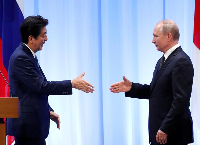Russian President Vladimir Putin (R) approaches to shake hands with Japanese Prime Minister Shinzo Abe at their news conference at G20 leaders summit in Osaka, Japan, June 29, 2019. REUTERS/Kim Kyung-Hoon/Pool
