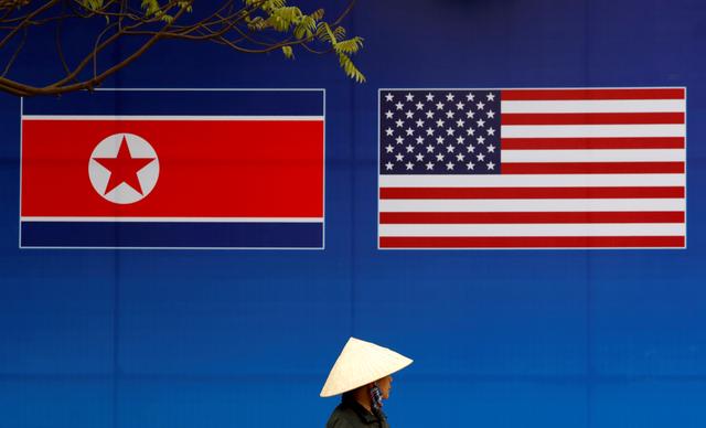 FILE PHOTO: A person walks past a banner showing North Korean and U.S. flags ahead of the North Korea-U.S. summit in Hanoi, Vietnam, February 25, 2019. REUTERS/Kim Kyung-Hoon/File Photo