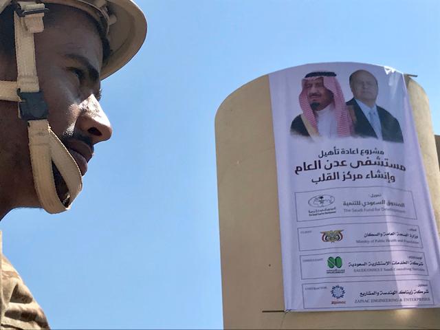 FILE PHOTO: A Yemeni soldier is pictured near a poster portraying Saudi Arabia's King Salman bin Abdulaziz Al Saud and Yemen's President Abdrabbuh Mansur Hadi outside a hospital renovated by Saudi Arabia in Aden, Yemen December 13, 2018. Picture taken December 13, 2018. REUTERS/Nael Shyoukhi/File Photo